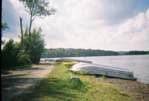 A photo of canoes lined up on the shore of a lake