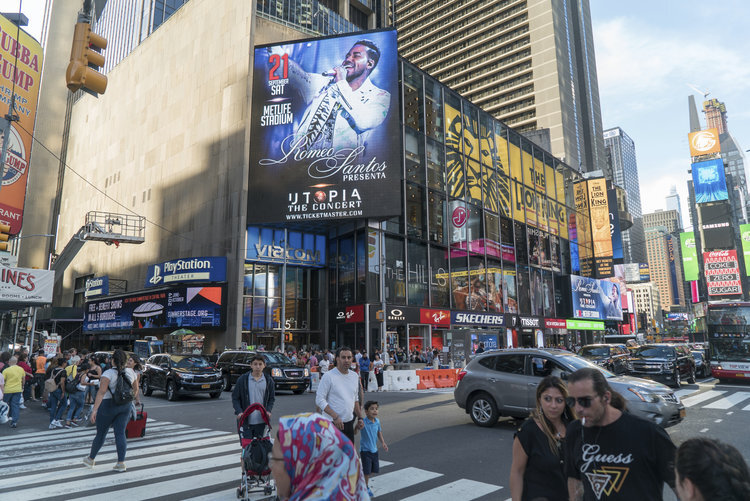 A street corner view in Manhattan of the A digital banner featuring an animated stage graphic promoting the 2019 SummerStage season at the Playstation Theater in NY